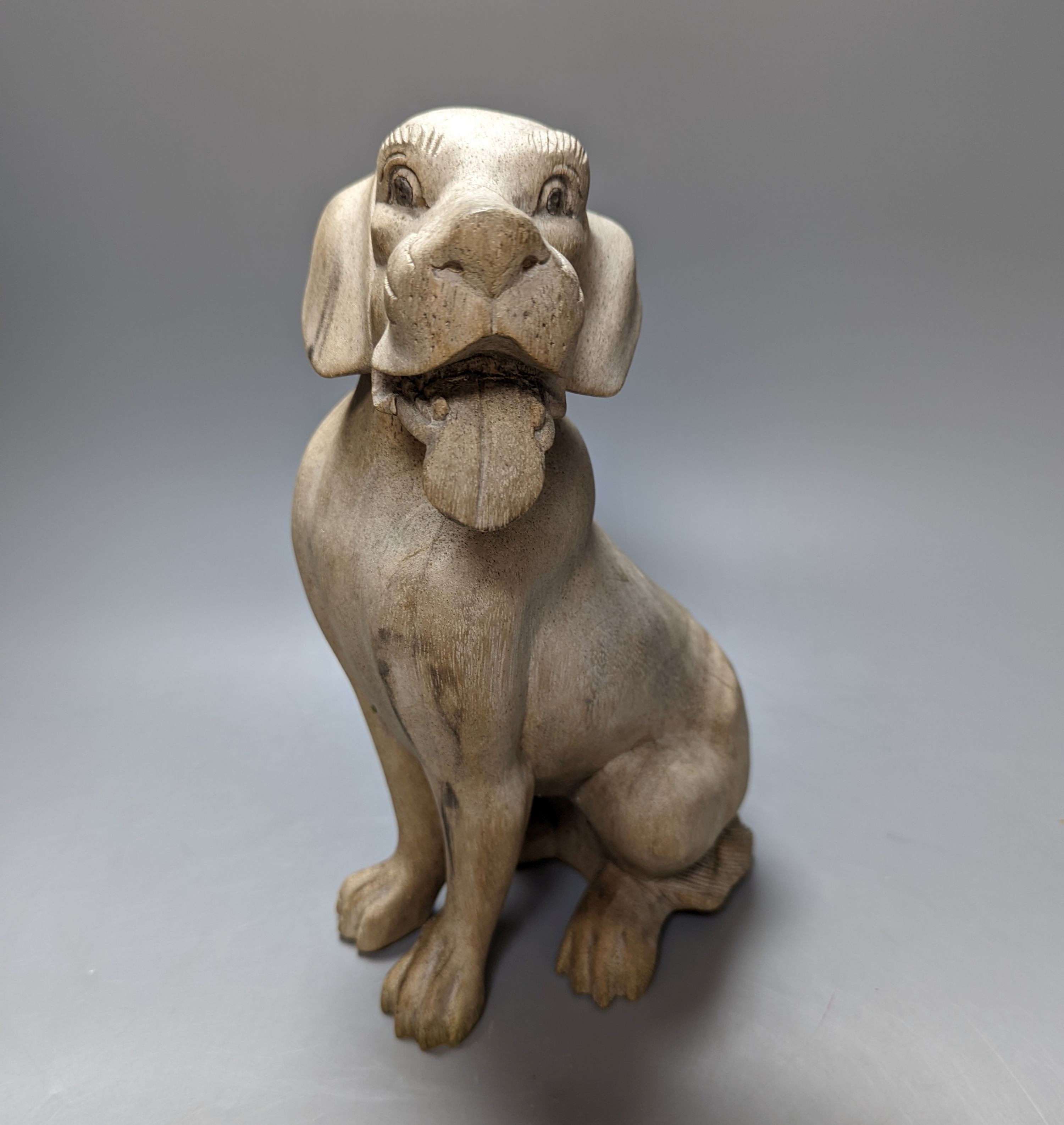 A carved wood model of a seated dog 29cm